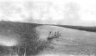 Člun se třemi muži přiráží ke břehu