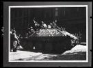 Fotografie, tank s muži a nápisem "Žižkov" projíždějící ulicí.