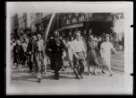 Fotografie, radostný dav prochází ulicí, v čele muž s československou vlajkou.