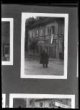 Fotografie, muž před domem, z jehož okna visí československá vlajka.