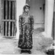 Židovská dívka stojící na dvoře, přes rameno má amulet