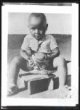 Fotografie, sedící domorodý černošský chlapec držící holuba