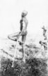 Muž stojící na jedné noze s četnými pažními náramky