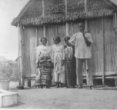 Malgašská rodina před svým domkem (rákosová chata na kůlech)