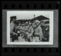 Fotografie, velitel před nastoupenými vojáky před vojenskými vozy