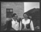 Kroje, 2 ženy, na dvoře Utanverdunes. Vpravo hospodářova sestra v kroji "upphlutm" Vlevo služka Lóa v kroji "peysunfät" Vpravo v pozadí ukázka, jak se staví drnová zeď