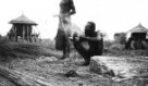 Dva muži připravují stavební materiál (slámu) na stavbu chýše, kmen Ňambara- Bari