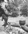 Žena loupe banány u ohniště s velkou nádobou, Babira