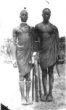 Dva muži stojící vedle sebe, jeden drží parier-shield, druhý antilopí roh jako hudební nástroj, Šilukové
