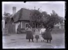 Ženy, chlapec a děvčátko před domkem s doškovou střechou