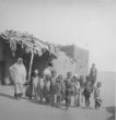 Skupina dětí před hliněným domem s přístřeškem