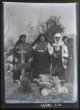 Tři ženy v kroji na hřbitově u hrobu s potravinami
