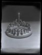 Vyobrazení naivní keramické majolikové miniatury: kruhový svícen, u svíčky klečí svatá rodina, po obvodu koledníci s dary a tři králové