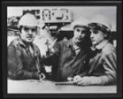 Fotografie, tři dělníci diskutují v továrně